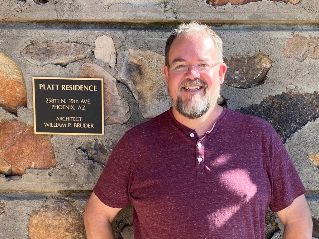 Outhouse Partner Stuart Platt in front of home his family built.