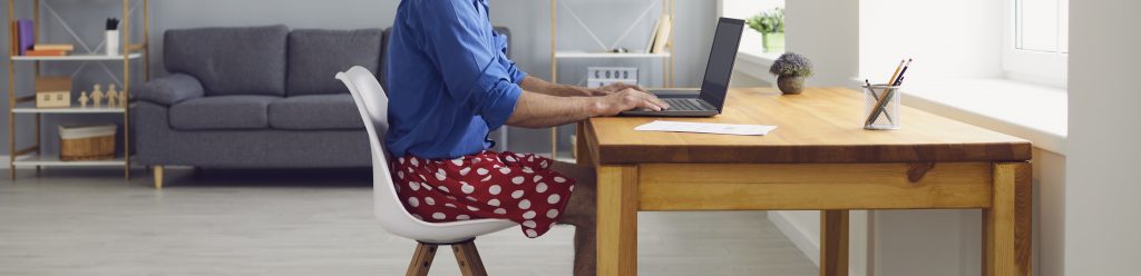 Online work at home. A young man typing on a laptop sitting at a table at home. 