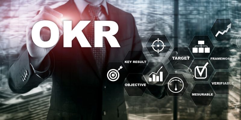 Letters OKR and graphs in front of man in suit