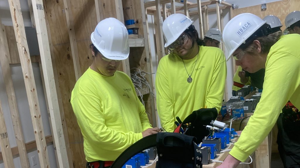 Closeup of three students at the Home Building Academy working with electrical parts
