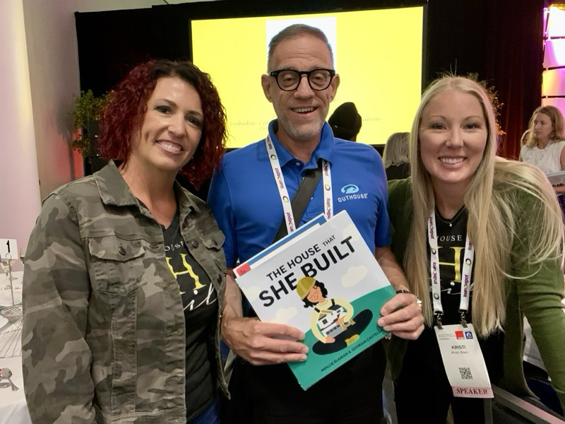 Jim Sorgatz, Outhouse VP Marketing holding The House That She Built book, flanked by Natalie Miles, owner of Natalie Miles Design, and Kristi Allen, owner of Woodcastle Homes