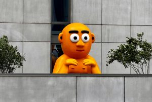 Orange sculpture, gray building, two trees