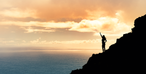 Mountain climber in shadow in front of a sunset