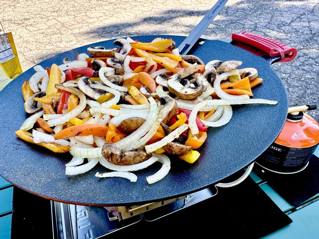 Fajitas cooking on a flat iron skillet.
