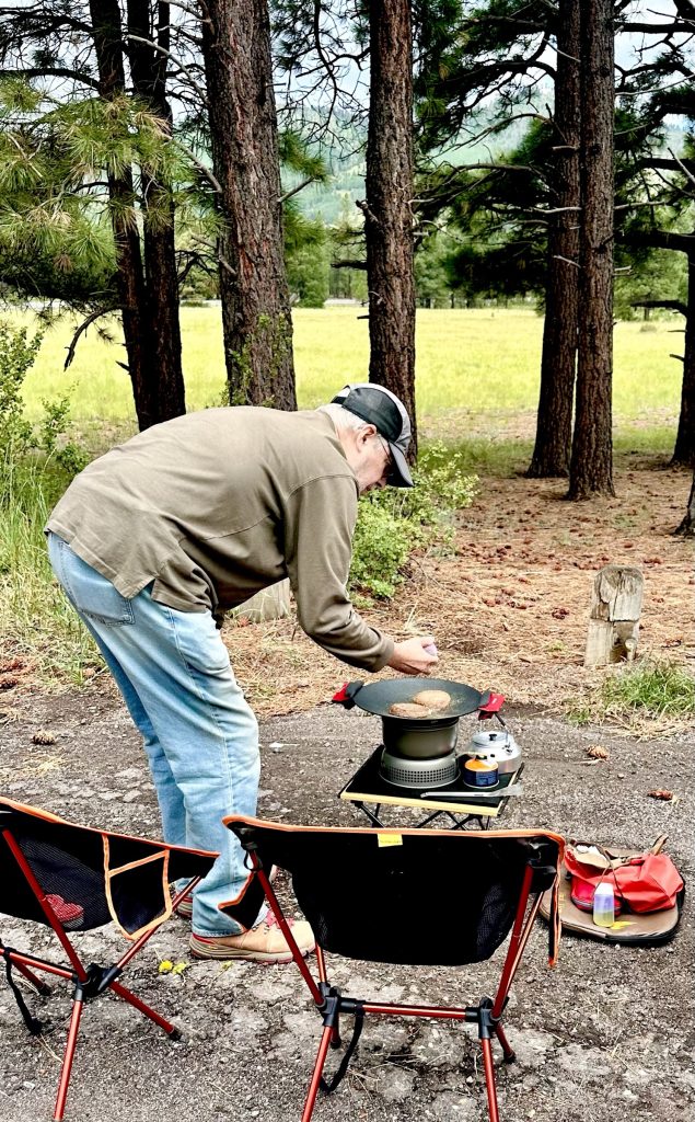 Man in forest leaning over a camp stove